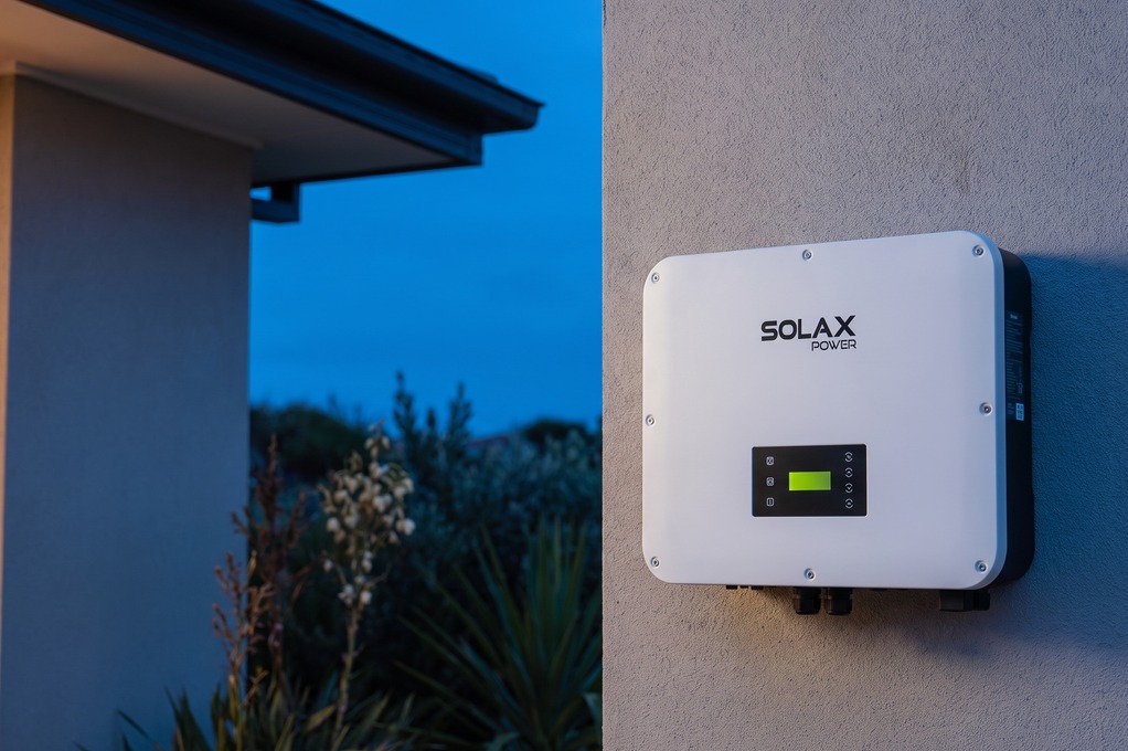 SolaX hybrid inverter at twilight with green LED ring, GRID and SYNC labels