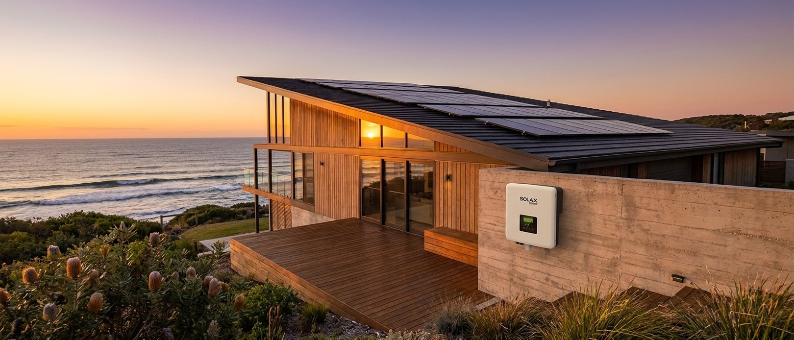 Coastal home with a full solar panel array on a pitched roof and a SolaX Power inverter on the rendered exterior wall at dusk.