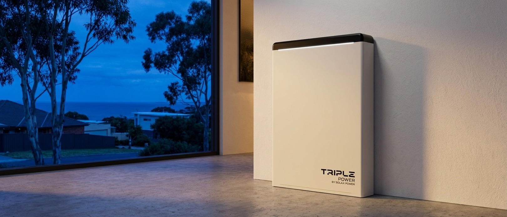Triple Power battery by SolaX Power standing against an interior wall at dusk, coastal suburb and gum trees visible through large window.